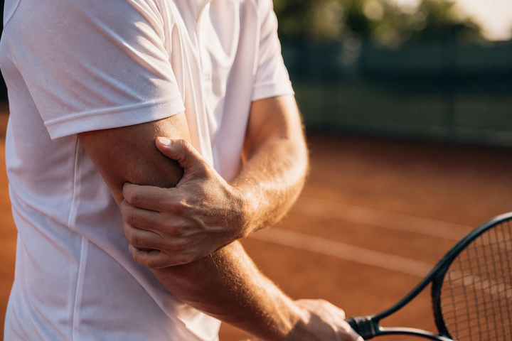Tennis player wearing the Pickle Armor elbow compression sleeve mid-swing